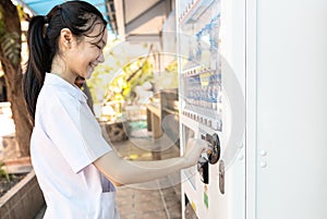 Asian people paying or buying hygienic drinking water from automatic vending machine in area lacking clean water,student inserting photo