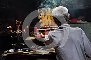 Asian people praying and burning incense sticks in a pagoda