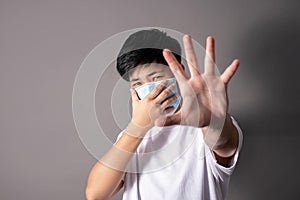 Asian people wear sterile medical masks on their faces and show a stop hand gesture to stop the spread of the virus, stop the