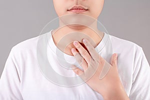 Asian people wear white T-shirts with a sore throat from a virus on a gray background