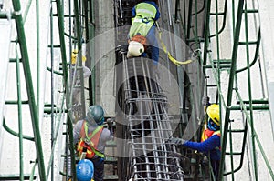 Asian people worker knitting metal rods bars into framework reinforcement for concrete pouring at construction site