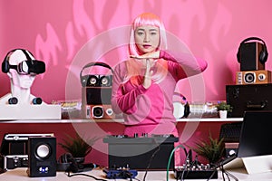 Asian performer standing at dj table doing time out gesture with palm while performing electronic song