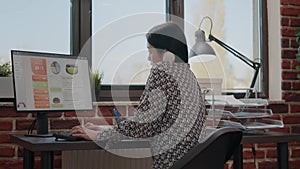 Asian person using office telephone while she works on computer