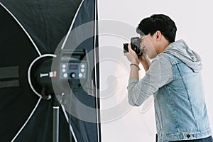 Asian Photographer aiming focus and shooting in Studio