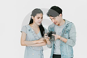 Asian Photographer and Asian female model looking pictures from back screen of DSLR camera with enjoying