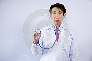 Asian physician holding stethoscope and examining over light blue background.