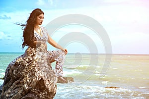 Asian plus size fat and overweight woman in a white dresses sitting on rock on the beach.