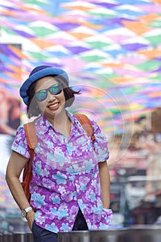Asian plus size LGBT tourist in Hawaiian shirt with sunglasses smiling on walking street