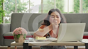 Asian plus size woman in casual eating working online with laptop computer online at home, eating unhygienic food