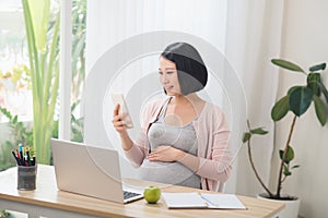 Asian Pregnant hard working, eatting and using the technology laptop together, preparing to be motherhood with good healthy photo