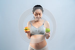 Asian pregnant woman choose healthy food or junk food