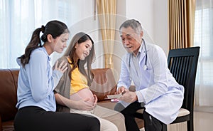 Asian pregnant woman and her friend visit gynecologist doctor at medical clinic for pregnancy consultant. The doctor explains the