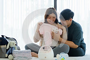 Asian Pregnant woman and her husband prepare baby monitor utensils, container preparation for pregnancy concept in bedroom at home