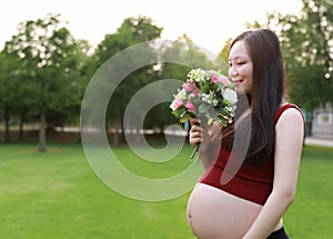 Asian pregnant woman hold Bouquet smell fragrance of flower  in garden forest lawn outdoor nature free relax happy sunshine