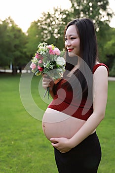 Asian pregnant woman hold Bouquet smell fragrance of flower  in garden forest lawn outdoor nature free relax happy sunshine