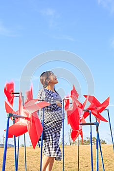 Asian pregnant woman in the middle of red pinwheel