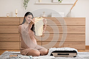 Asian pregnant woman preparing diaper,feeding bottle for baby at home.Pregnant woman packing baby stuff ready for the maternity