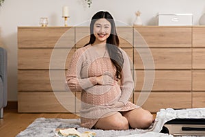 Asian pregnant woman preparing diaper, feeding bottle for baby at home. Pregnant woman packing baby stuff ready for the maternity