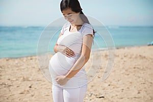 Asian pregnant woman smile while touching her belly