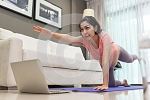 Asian Pregnant woman stretching and practicing yoga with online class on laptop