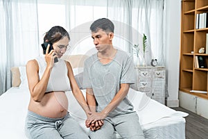 Asian pregnant woman talking on mobie phone with the doctor