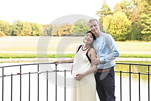 Asian pregnant women and caucasian husband standing near water