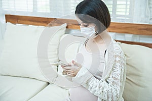 Asian pregnant women wearing medical mask due to illness, dizziness using smart mobile phone with worry, pandemic Wuhan