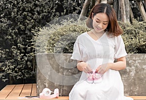 Asian prenant mother holding pink girl& x27;s shoes