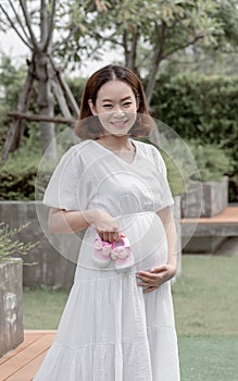 Asian prenant mother holding pink girl& x27;s shoes