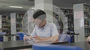 Asian preteens boys using tablet computer at library .