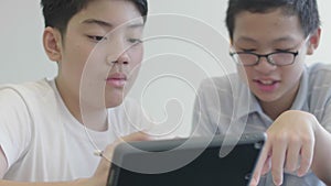 Asian preteens boys using tablet computer at library .