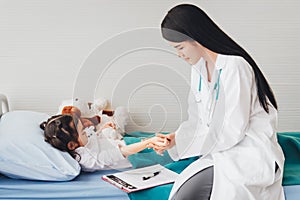 Asian pretty doctor woman holding the wrist of the girl patient To measure heart rate