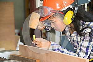 Asian pretty female carpenter using wood hammer.