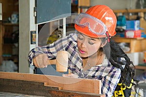 Asian pretty female carpenter using wood hammer.