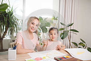 Asian pretty young mother and her daughter paining the plaster doll together