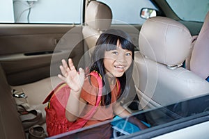 asian primary pupil student sitting in the car and waving good bye