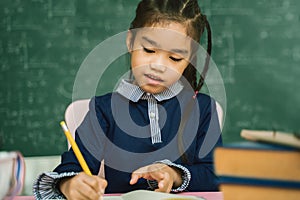 Asian primary school student studying homework in classroom.