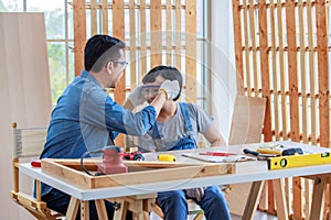 Asian professional carpenter engineer architect woodworker dad in jeans outfit with safety goggles gloves touching young boy son