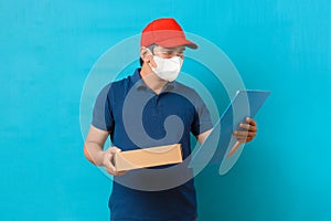 Asian Professional Delivery man wearing face mask holding checking list with cardboard boxes