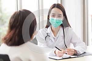 Asian professional doctor woman talks with her patient while she wears medical face mask in hospital at health care,pollution PM2.