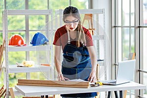 Asian professional female engineer architect foreman labor worker wears safety goggles glasses using pencil and square angle