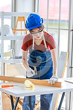 Asian professional female engineer architect foreman labor worker wears safety goggles hard helmet and jeans apron using steel
