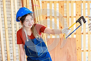 Asian professional female engineer architect foreman labor worker wears safety goggles, helmet, apron and gloves standing smiling