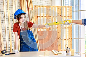 Asian professional female engineer architect foreman labor worker wears safety goggles, helmet, apron and gloves standing smiling