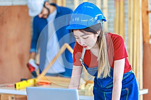 Asian professional female engineer architect foreman labor worker wears safety goggles and jeans apron standing smiling using