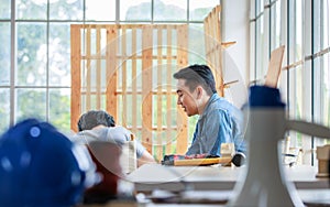 Asian professional male carpenter woodworker engineer dad in jeans outfit with safety gloves and goggles helping teaching young