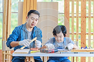 Asian professional male carpenter woodworker engineer dad in jeans outfit with safety gloves holding small home model teaching