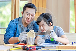 Asian professional male carpenter woodworker engineer dad in jeans outfit with safety gloves holding small home model teaching