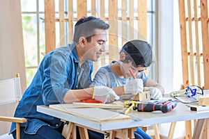 Asian professional male carpenter woodworker engineer dad in jeans outfit with safety gloves holding small home model teaching