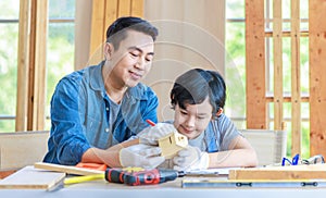 Asian professional male carpenter woodworker engineer dad in jeans outfit with safety gloves holding small home model teaching